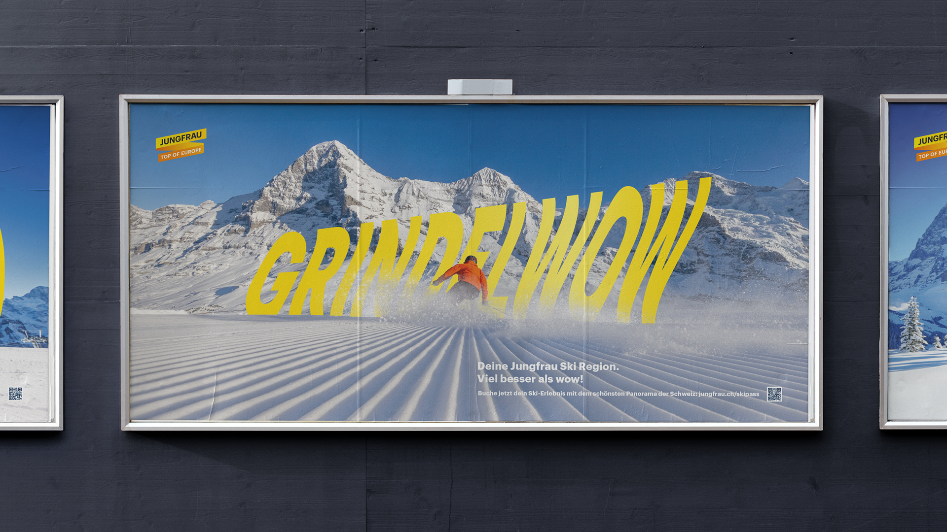 Plakat mit gelbem Schriftzug ‚GRINDELWOW‘ vor verschneiter Bergkulisse in der Jungfrau Ski Region