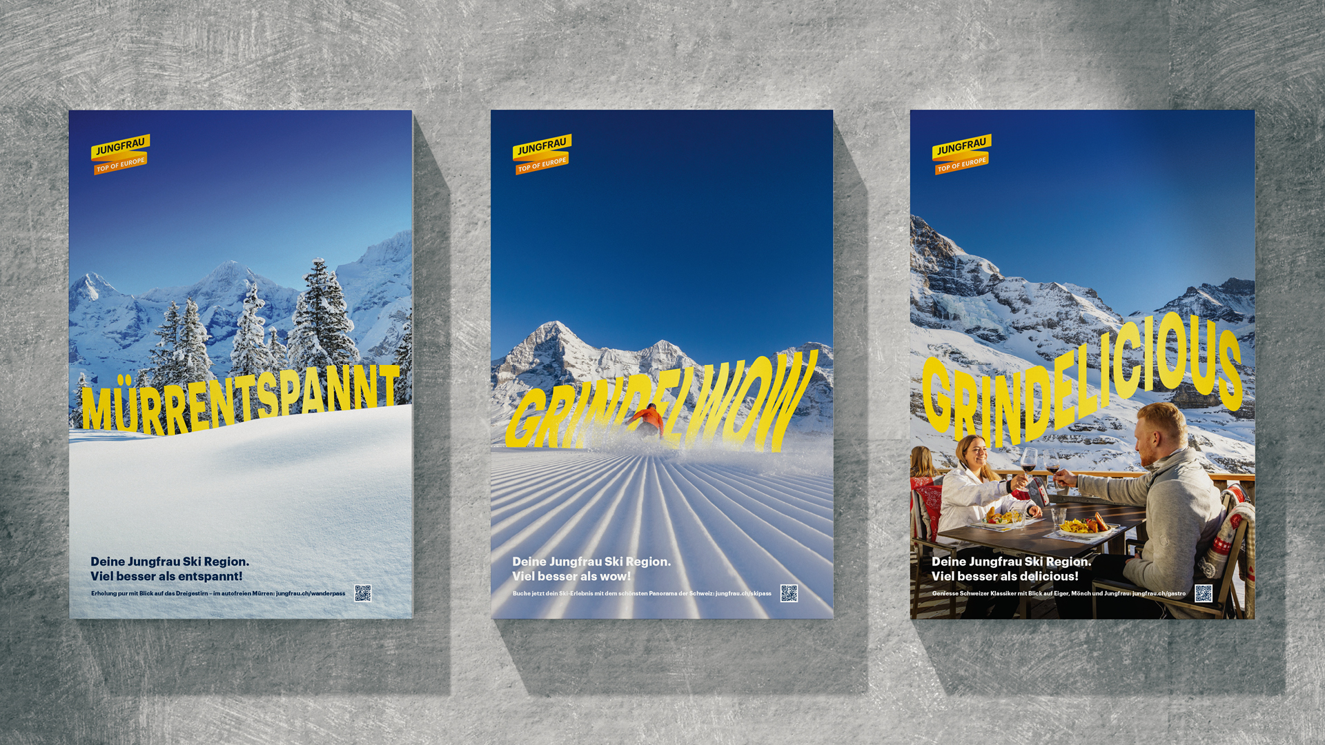 Drei Werbeplakate der Jungfrau Ski Region mit Wortspielen: „Mürrentspannt“ vor verschneiten Tannen, „Grindelwow“ mit Skifahrer auf der Piste, und „Grindelicious“ mit einem Paar beim Essen auf einer Sonnenterrasse mit Bergpanorama.