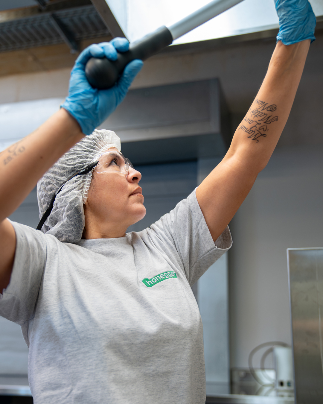 Eine Angestellte von Honegger reinigt eine Wand in Arbeitskleidung.