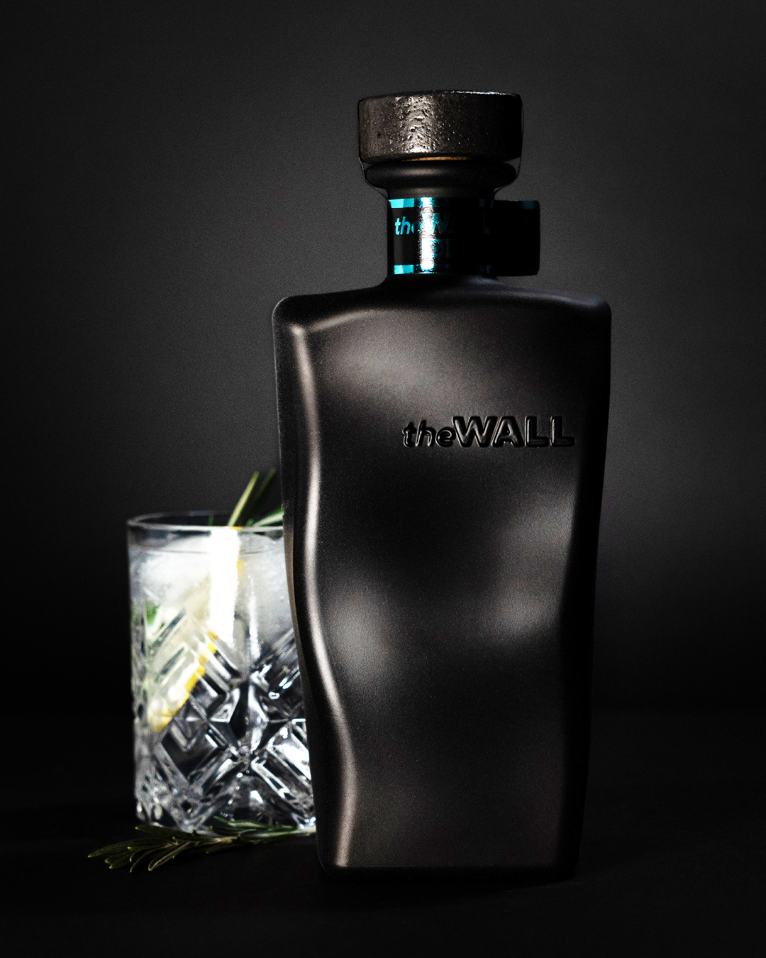 Fotografie auf dunklem Hintergrund des The Wall Gins mit Serviervorschlag eines Gins mit Zitrone.
