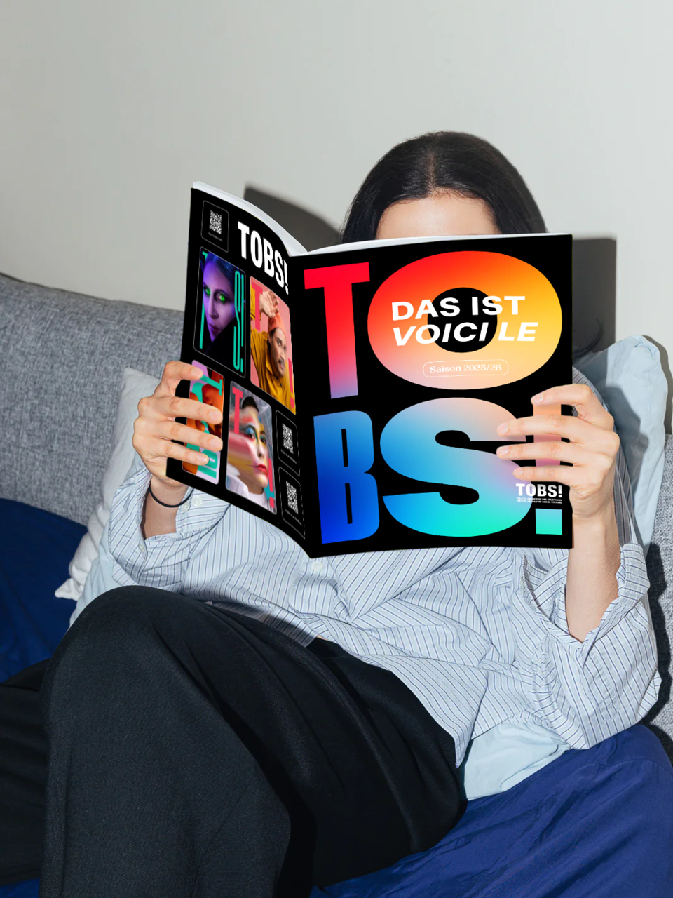 Eine Frau, die sich lesend hinter dem TOBS Magazin verbirgt.